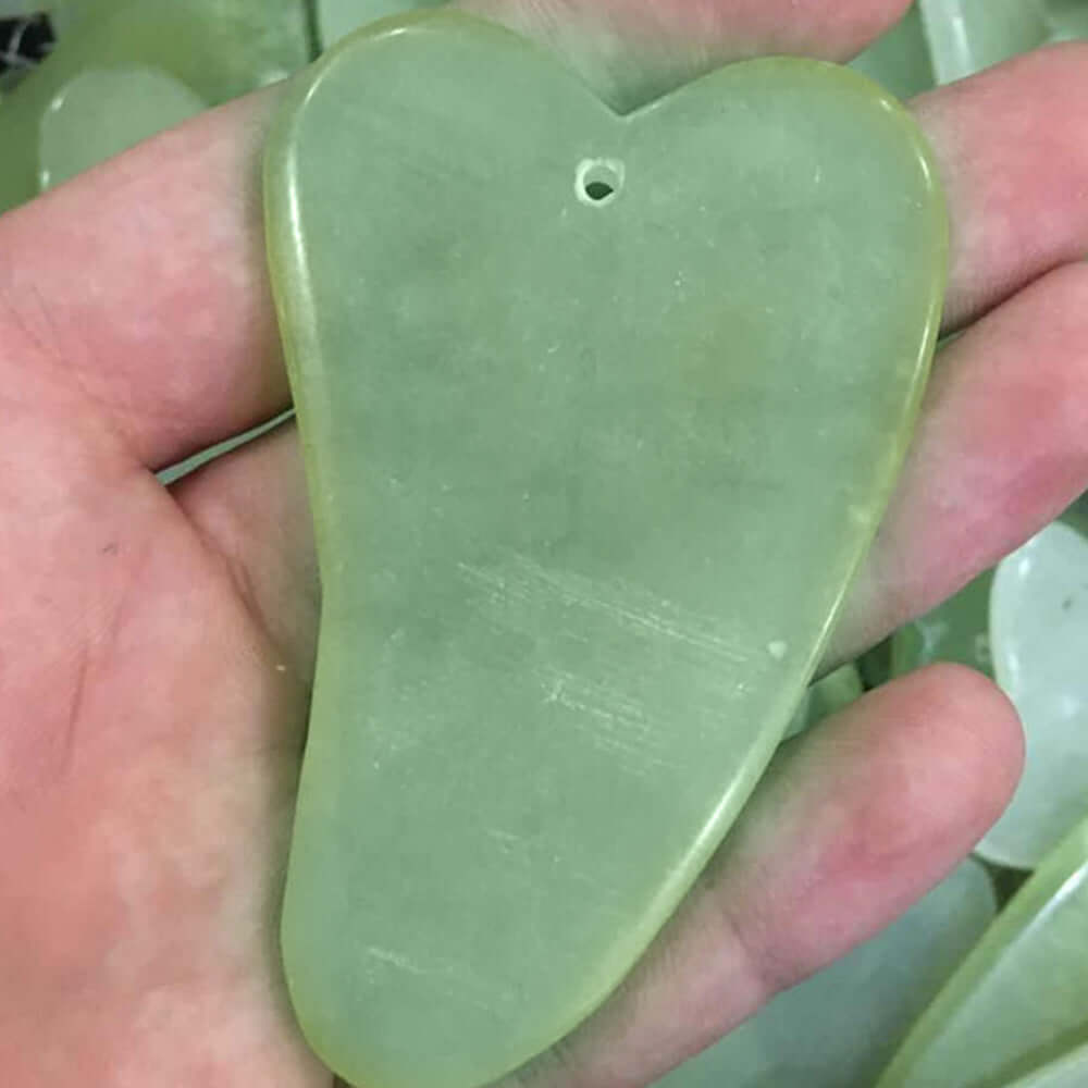 Natural jade heart-shaped massage scraper used for skin elasticity and circulation in beauty routines.